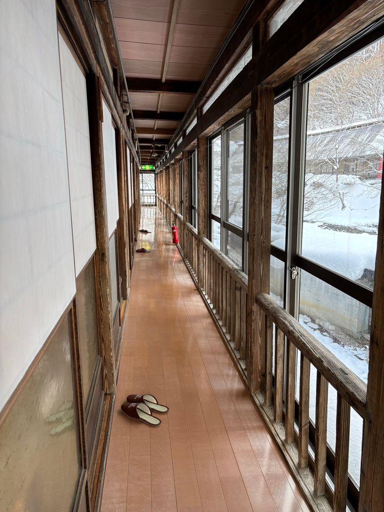 宿の廊下。使い込まれた木造建築。外は雪景色。