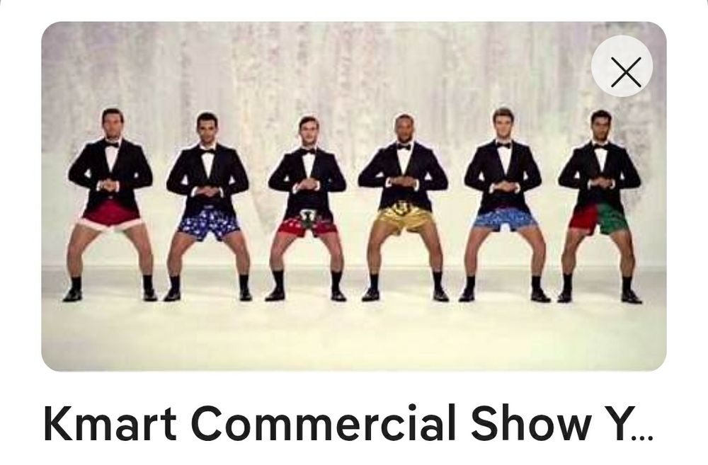 Six men standing in a row, each wearing formal black tie on the top and festive boxer shorts on the bottom.