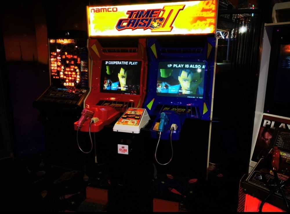 Time Crisis 2 arcade machine in arcade with dark lighting.