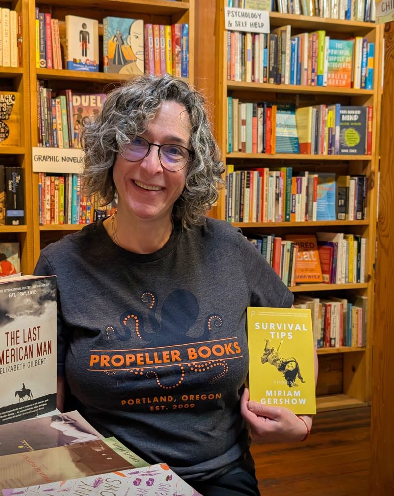 A photo of me in my @propellerbooks T-shirt holding Survival Tips at Cottage Groove books. 