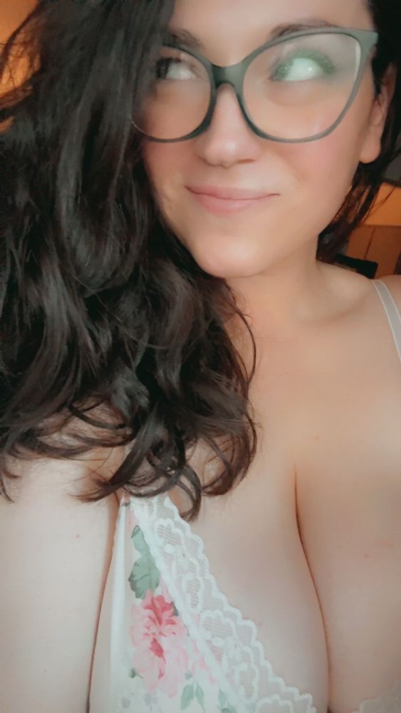 me, white lace floral negligée, dark hair down, smirking and not making eye contact bc autism. 
