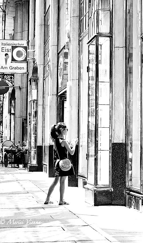 A young female with ponytail looking at shop windows.