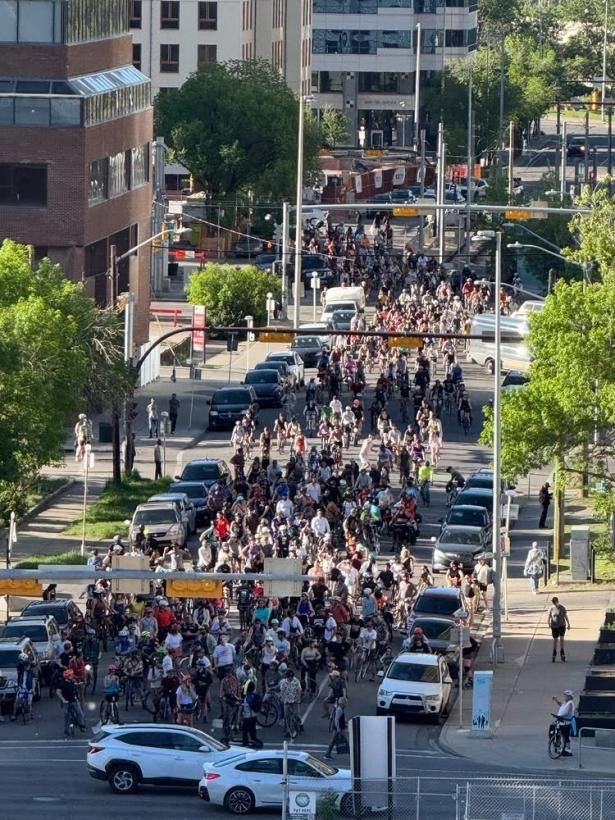 A group of hundreds of people on bikes stopped at an intersection. 