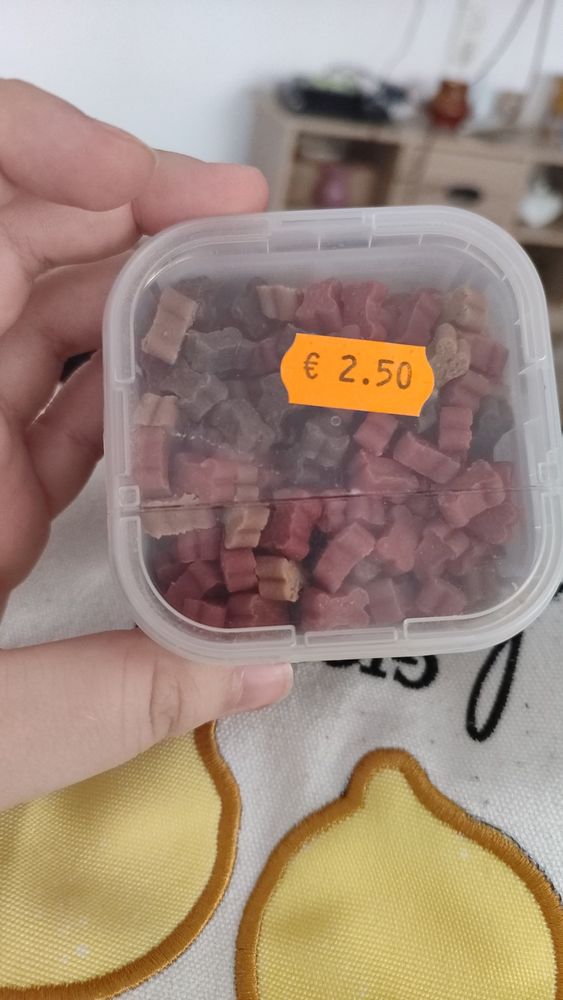 Una cajita transparente con 140 gr de chuches de perro (muy pequeñas y abundantes) de colores marrón, ocre y rojo. Hmmm, delish.