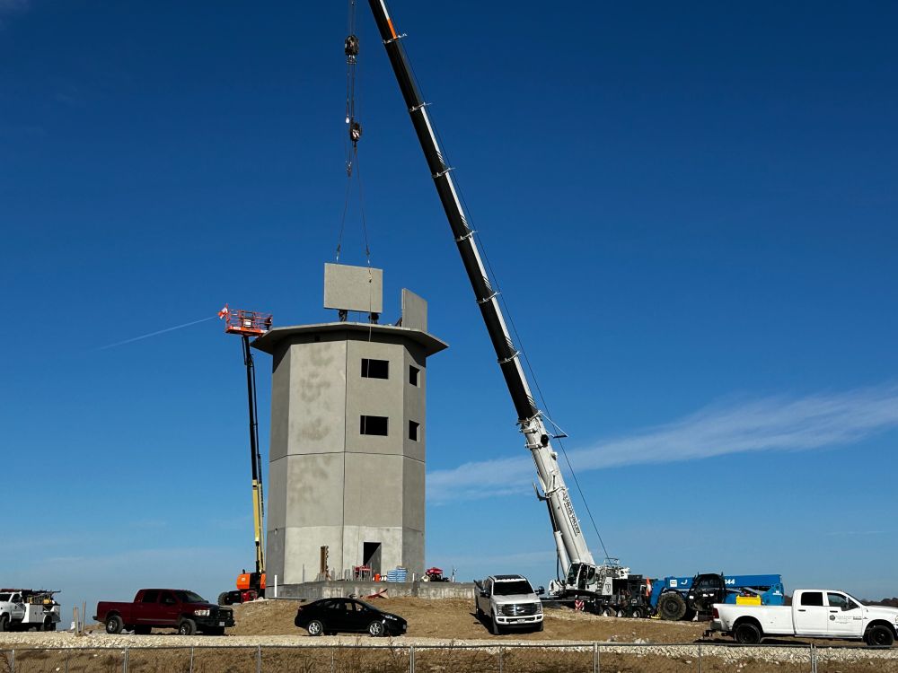 Two workers are seen steadying the lifted panel into place.