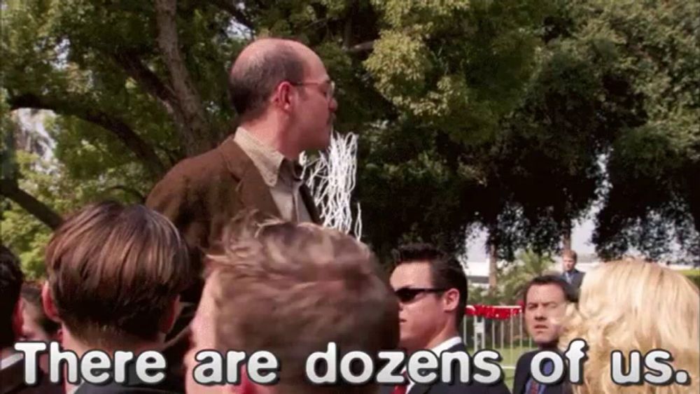 a man in a suit and tie stands in front of a group of people and says there are dozens of us