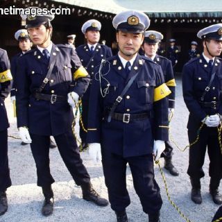 Japanese police uniform, featuring the distinctive cross-shoulder harness, formal tie and yellow armband.