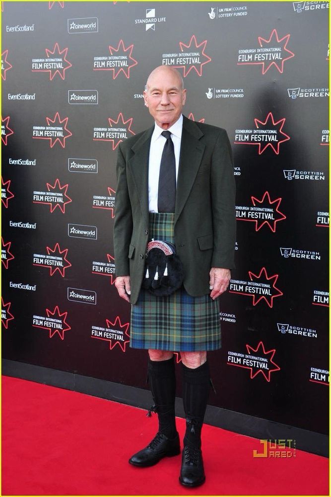 Patrick Stewart on a red carpet wearing a jacket and tie and kilt and sporran