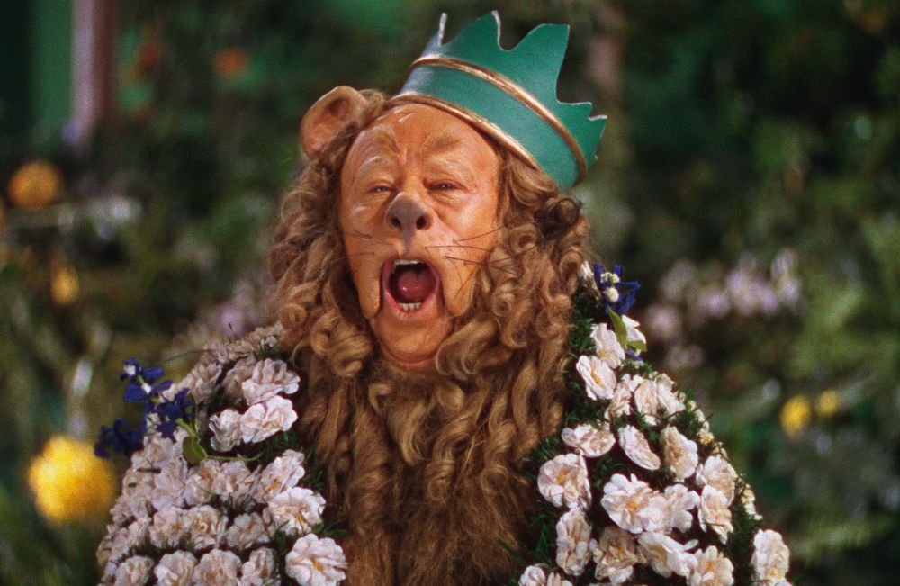 Burt Lahr as The Cowardly Lion in The Wizard of Oz, singing about being King of the Forest wearing a broken flowerpot as a crown and a flowery cape