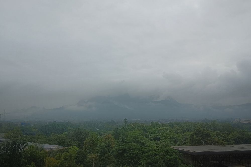 A photograph showing hills draped in mist and cloud. Green stretch from the foothills to our building. 
