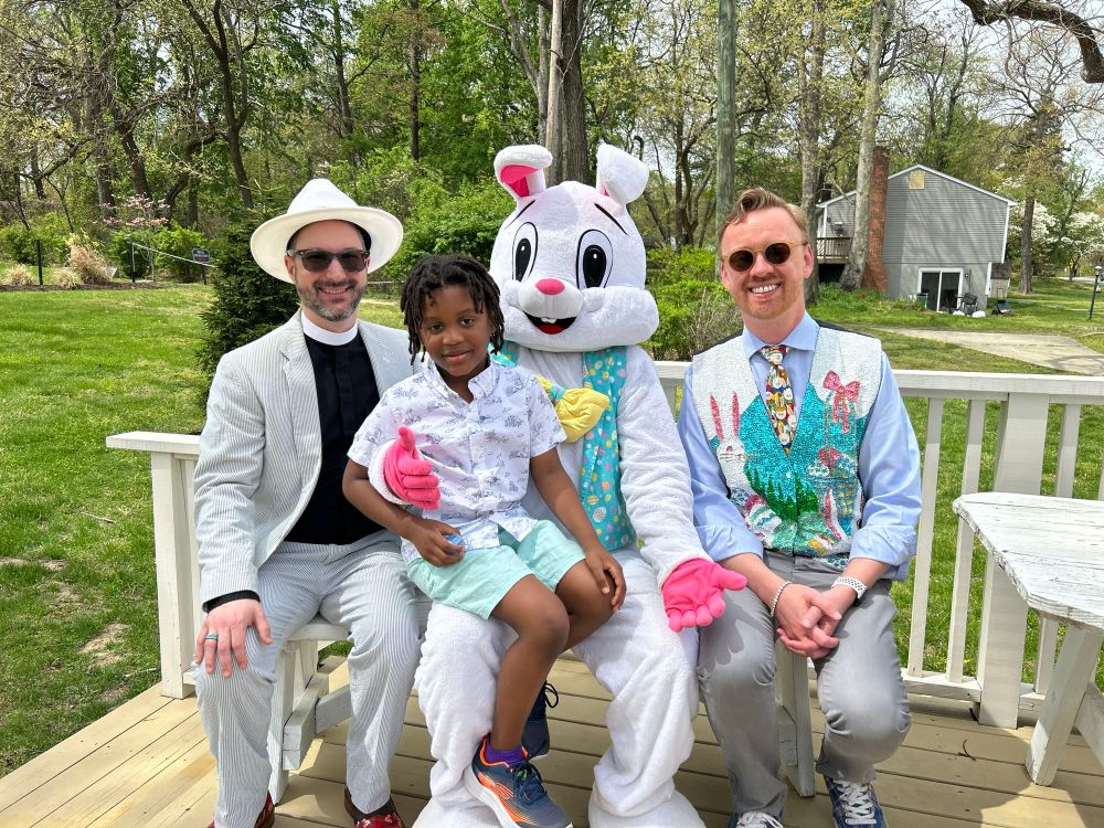 A family is sitting on a bench outdoors with the Easter Bunny.
