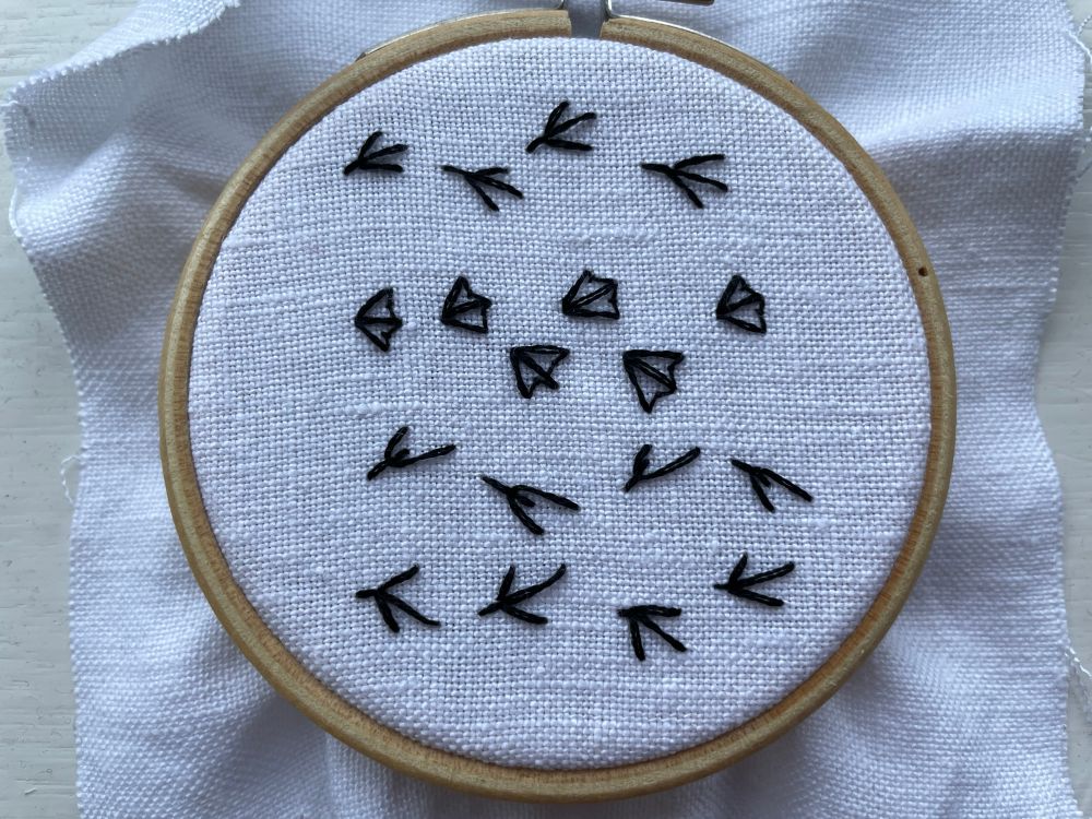 Bird tracks embroidered on white linen.