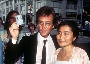 John Lennon with Yoko Ono, displaying his newly-acquired Green Card on 7 Oct 1976.
