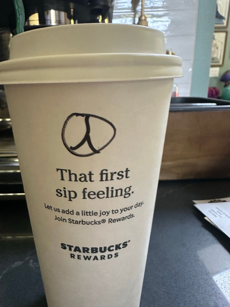 “peace” sign on a starbucks cup that’s really the mercedes logo