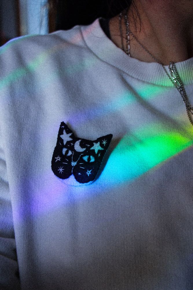 Broche mignonne chat astral en feutrine cousue main. Petit chat noir et blanc avec des étoiles et lunes sur le front
