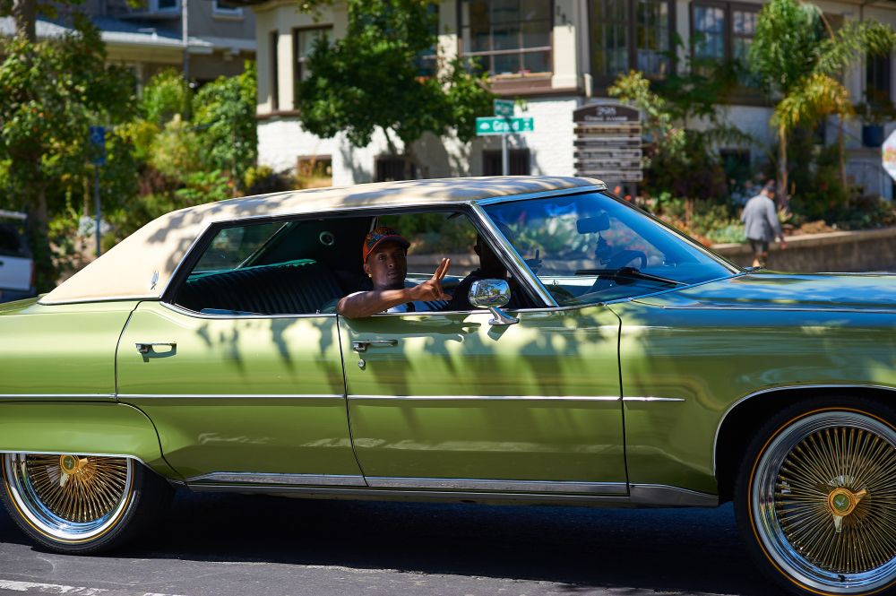 Passenger in a vintage car drives by and waves