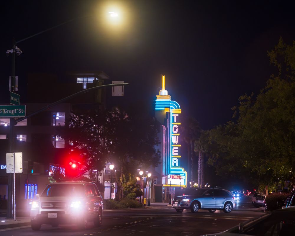 Large Tower theater neon sign in background. Cars and traffic lights in the foreground.