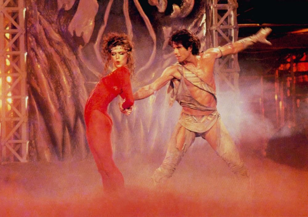 A still from the film STAYING ALIVE featuring Finola Hughes and John Travolta dancing on a smoky stage 