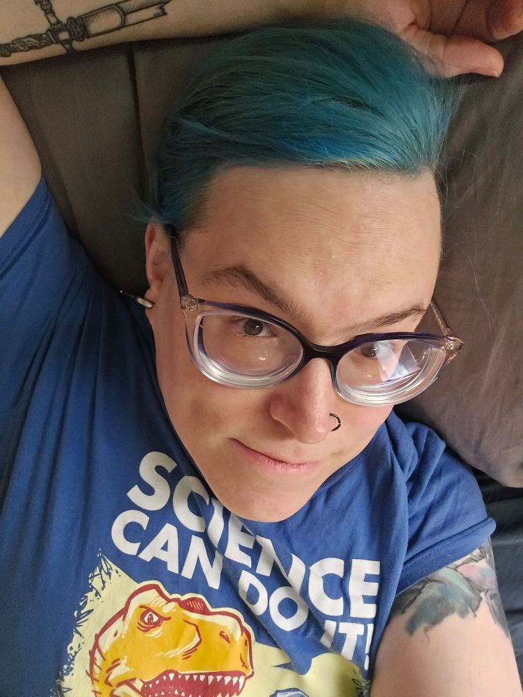 blue-haired girl lying on a bed, head on a pillow