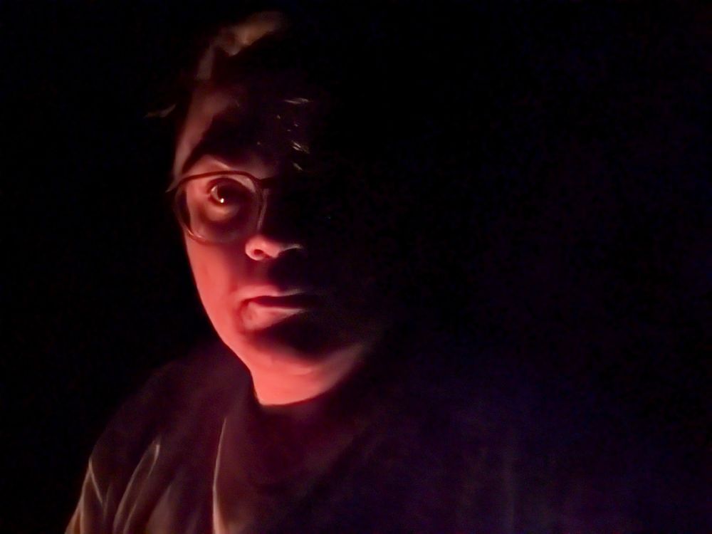Selfie, illuminated by firelight.