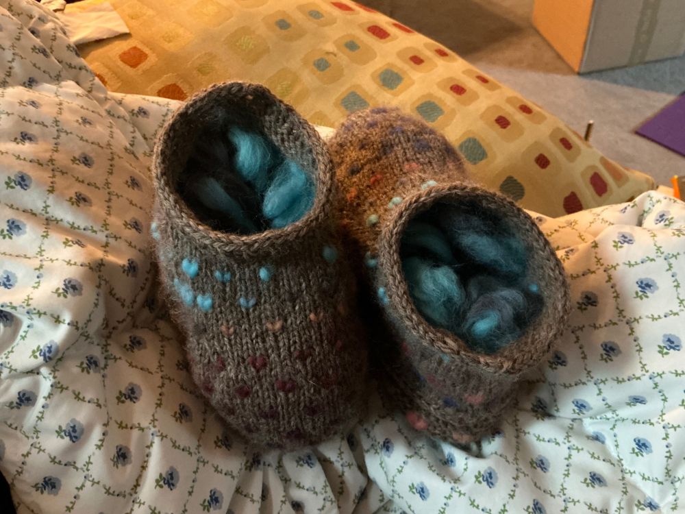 Knitted thrummed slippers pointing in opposite directions.