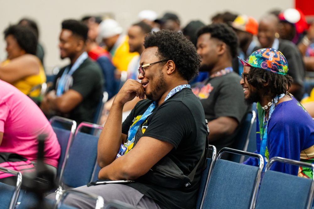 A young black man in a Black shirt and gray pants is seen laughing during the panel “Breaking Barriers in Animation: A Conversation with Martian Blueberry.”  This panel took place during Dream Con in Houston, Texas during the last weekend of May 2025.

Trust me.  The jokes were FLYING.