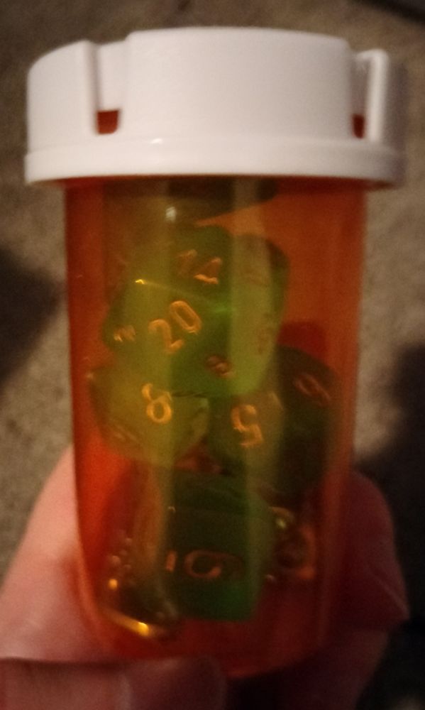 Various blue-green dice inside of an orange safety cap pill bottle.