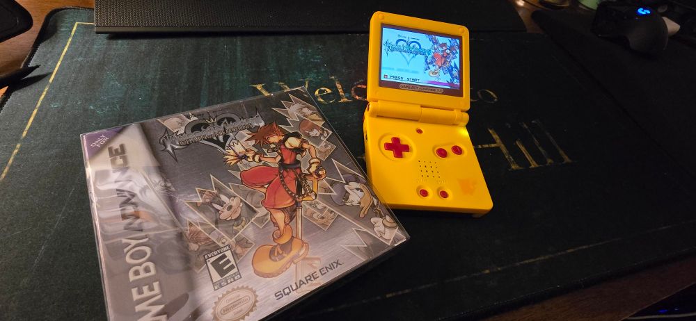 A special edition custom Pikachu GBA and a CIB copy of Kingdom hearts Chain of Memories for the GBA laying on a Silent Hill Mouse pad.