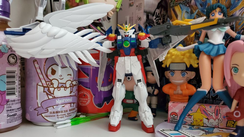 HG Wing Gundam Zero, arms spread, featuring the SD EW Winged Twin Buster Rifle in one hand with regular Twin Buster Rifle in the other