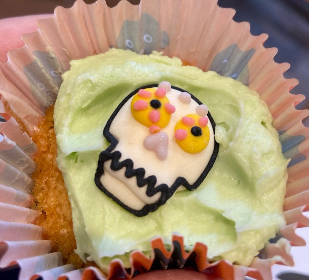 A cupcake with green icing with a skull on top