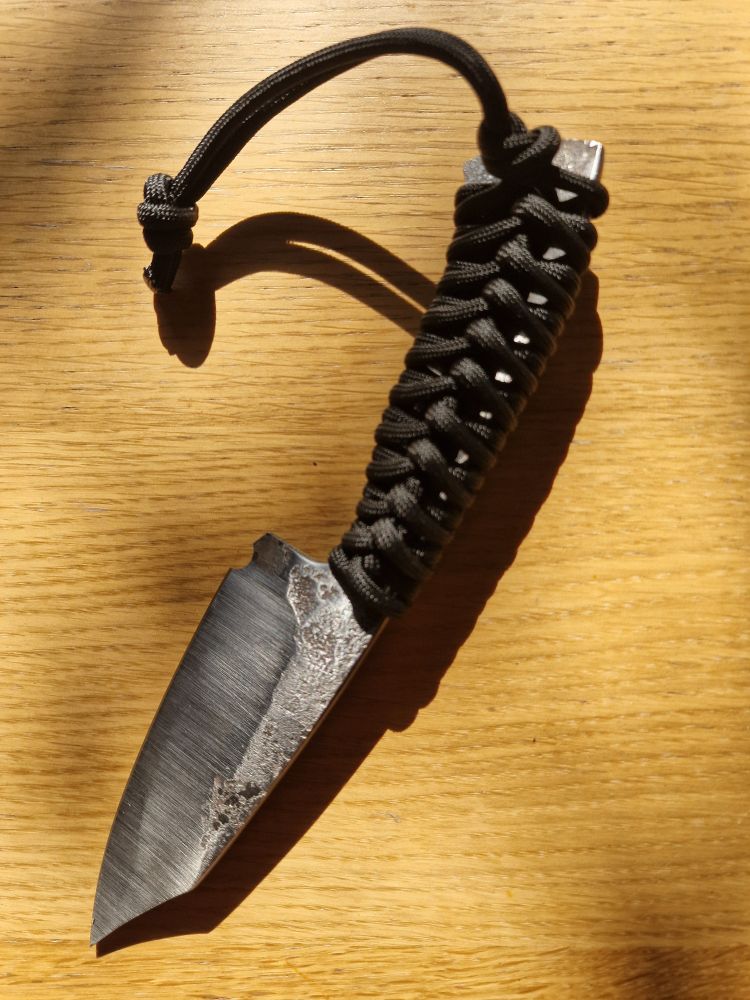 A somewhat roughly made but functional steel knife with a paracrod wrapped handle. 