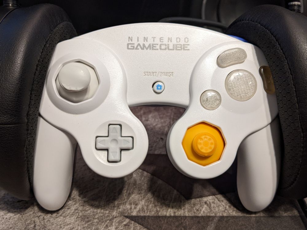 Another Phob 1 build using better donor parts and a white shell, which is my main controller. I designed and printed the Y/A/B buttons, with the Y button having a custom slope for my claw-like grip. The start button is replaced with a home button from a Wii-era Controller. The right trigger is also shaved down and smoothed over, but that isn't pictured. The left stick is from a Nunchuk, with signs of wear. The right (C-stick) rubber is worn to the plastic. The X button was a one-off cast from resin as a quick experiment to learn about making silicone molds.
