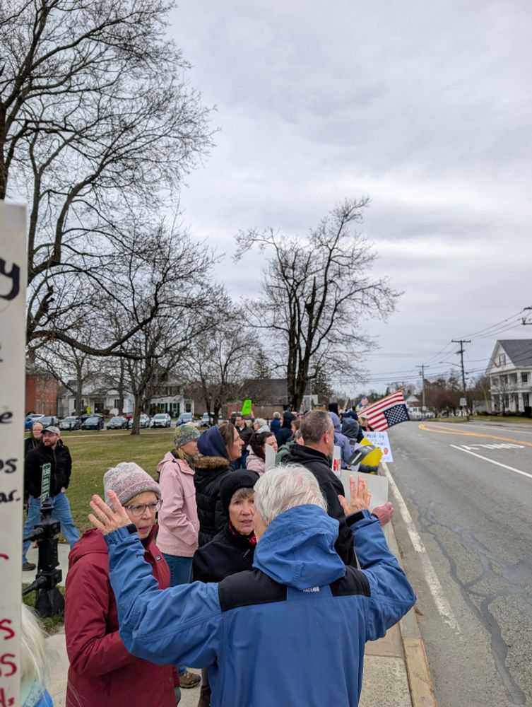 Crowds with signs line the outside of town common. 