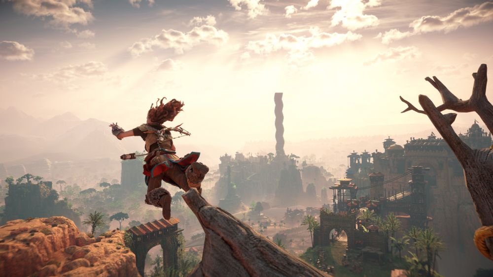Aloy as she starts leaping from a rappel point near the access bridge to Meridian which is visible in the background.