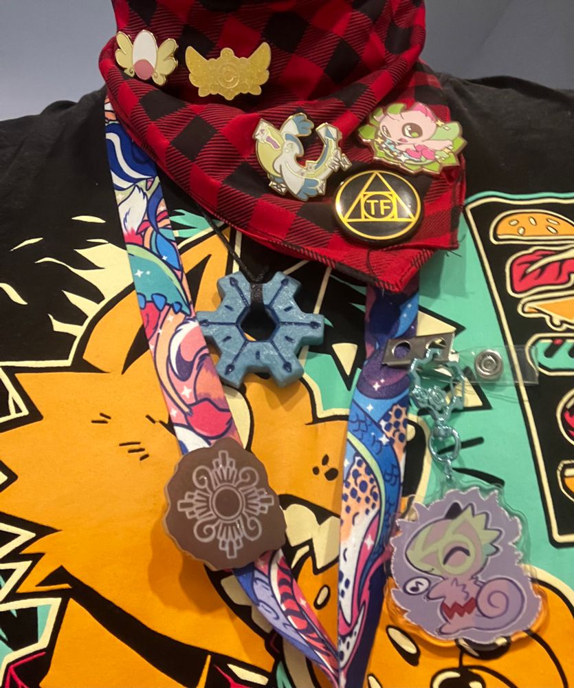 A dude wearing a whole fuckload of pmd fan merch on a scarf, including explorer badge pins, a relic fragment, a time gear necklace, and a pin that says “tf”