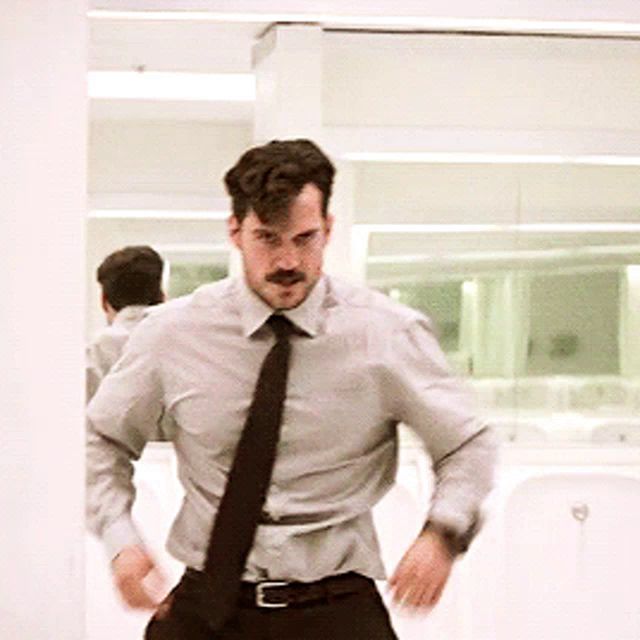 a man with a mustache wearing a shirt and tie is dancing