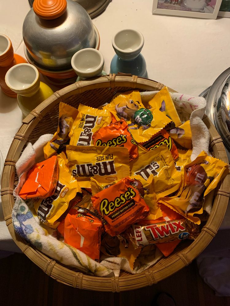 A big basket full of fun-sized candy including peanut M&Ms and Reese's peanut butter cups