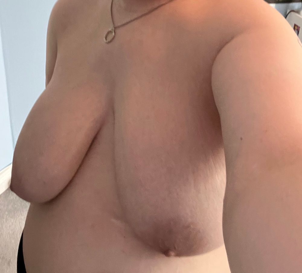 Leo is taking a selfie from the right side. He is topless, his bare tits visible. He’s wearing a silver necklace with a silver band charm and black underwear. His face isn’t visible.