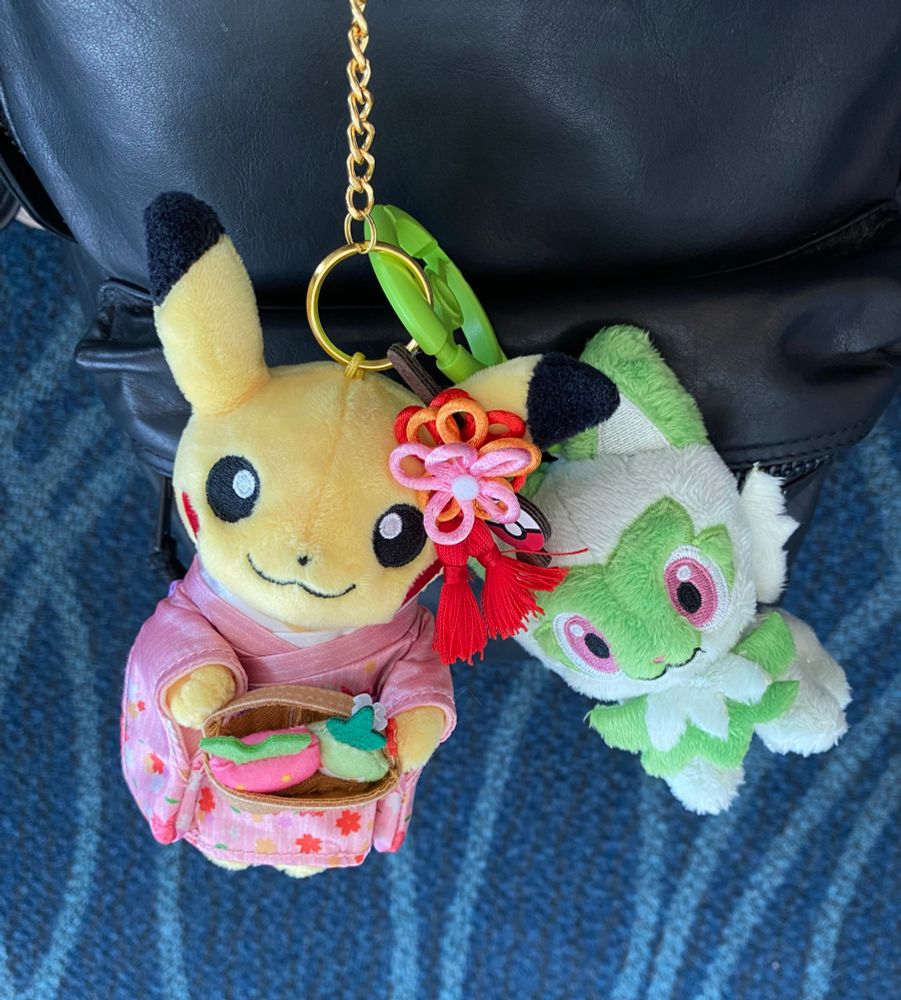 A pikachu Kyoto special plush keychain and a sprigatito plush keychain on a backpack 