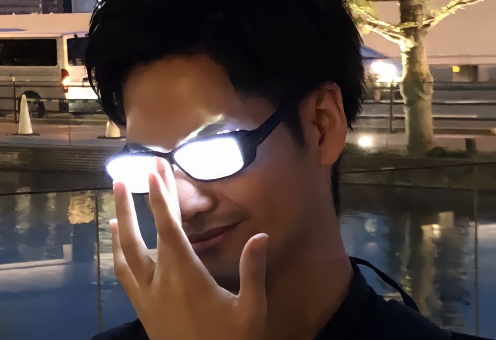 a person placing their hand to the glasses on their face and the lens are glowing bright white. 