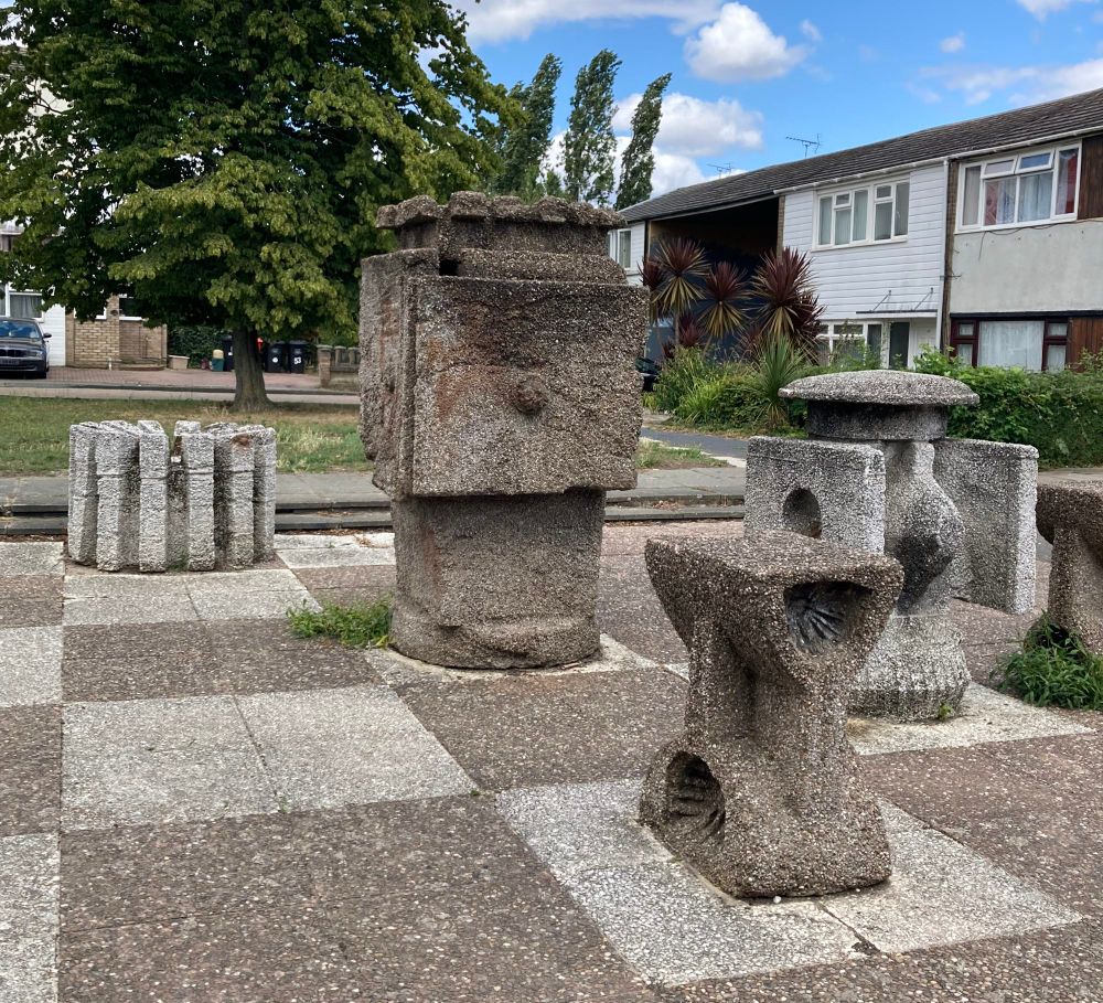 Concrete chess pieces on a chess board in a suburban estate 