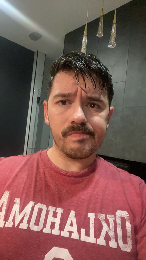 man (me) with a red Oklahoma OU Sooners (football) t-shirt on looking into the camera. 