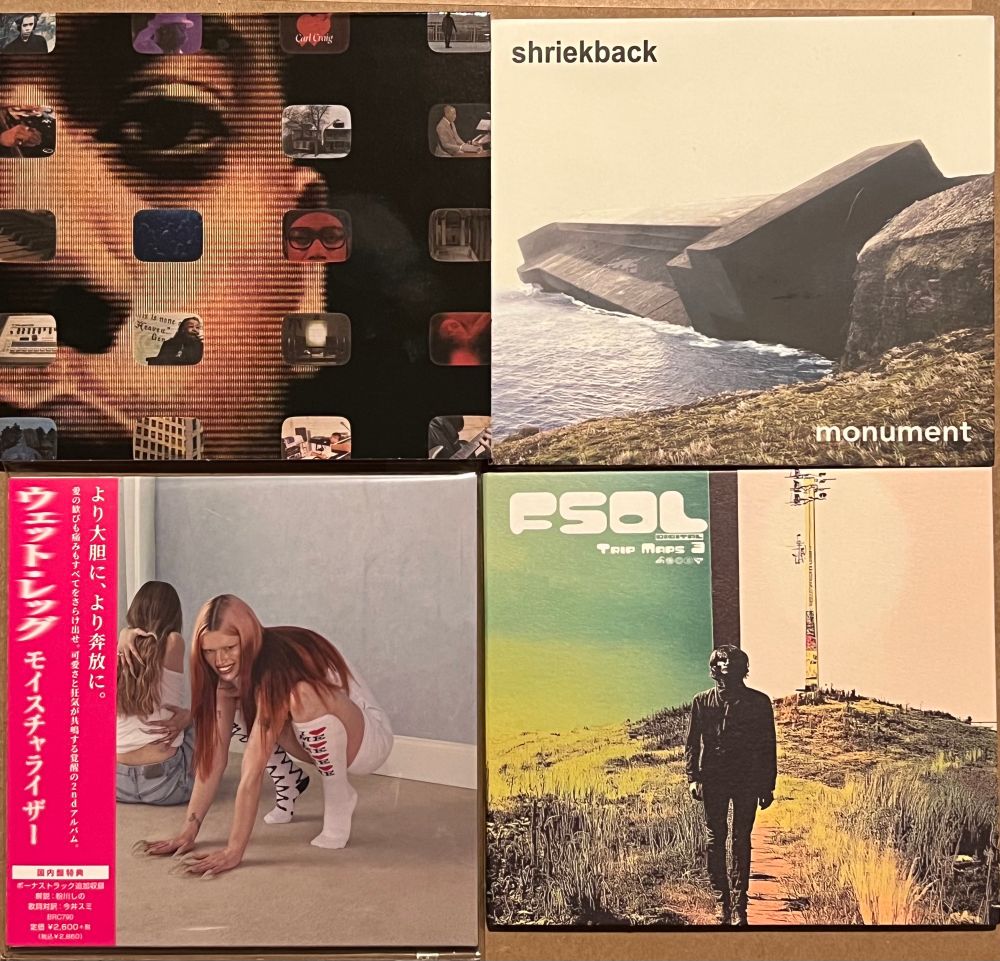 Four CDs arranged in a 2x2 square. Clockwise from top-left: The “Desire: The Carl Craig Story” soundtrack, “Monument” by Shriekback, the “Trip Maps 3” mix CD by Future Sound Of London, and the Japanese CD of “Moisturizer” by Wet Leg. 