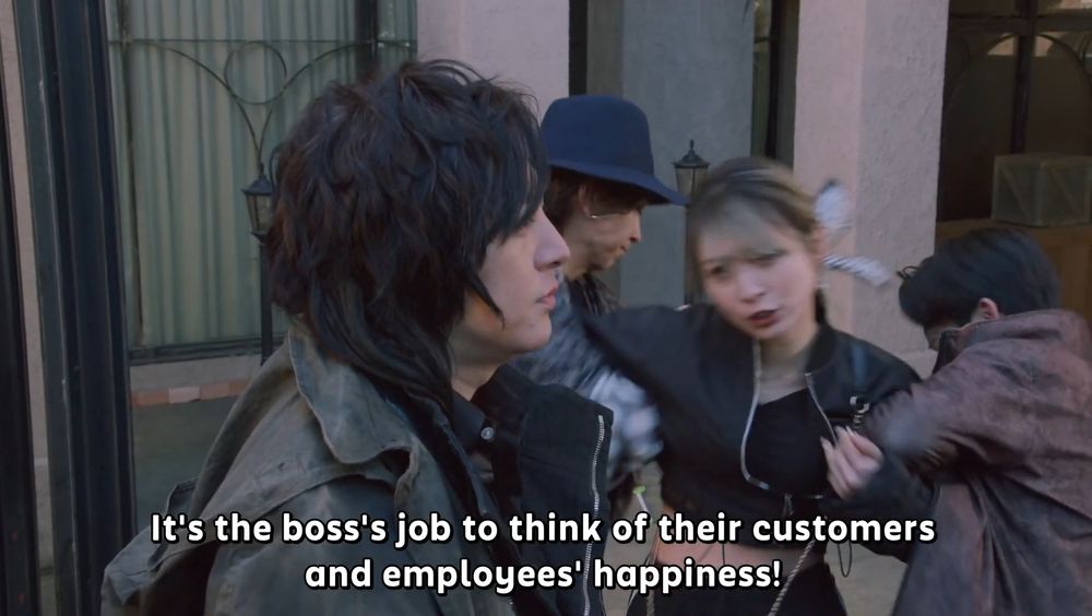 Sachika Amane from Kamen Rider Gavv confronts Lango Stomach as she gets pulled away from him by Rakia and Hanto Karakida. The subtitles read "It's the boss's job to think of their customers and employee's happiness!" 