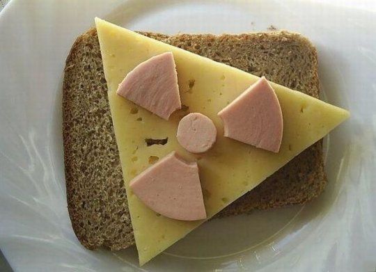 Sausage cut in the shape of a radioactive sign with cheese and bread in the background.