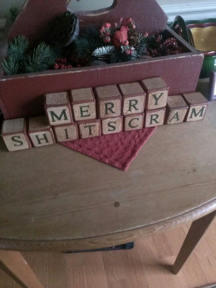 A set of wooden letter blocks on a table, arranged to spell out "Merry Shitscram"