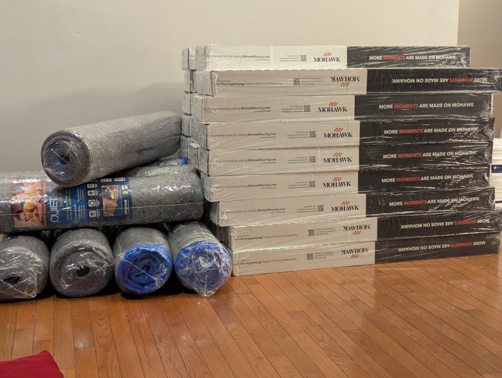 Some quiet pad rolls for flooring on the left, and many stacks of engineered laminate flooring in the right. 