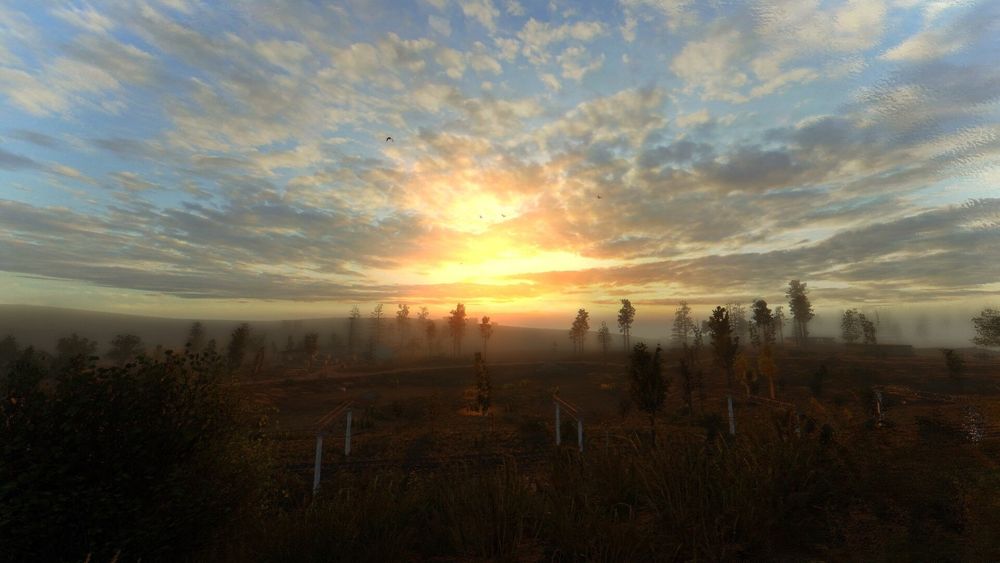 Stalker oyunundan bir screenshot. Manzara fotoğrafı. Görselin yarısı gök, diğer yarısı sisli ve puslu bir kırsal. Kırsalın ortasından tren rayları geçiyor. Gök yüzü turuncudan maviye bir çok renkte, parçalı bulutlar var, güneş batıyor.