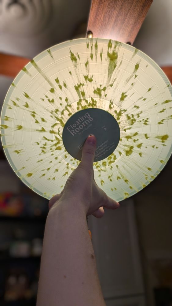 Held up to the light, the vinyl's main green is semi-translucent with the yellow splotches standing out against the back glow.