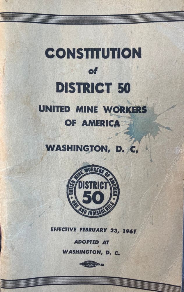 The stained white cover of a booklet titled “Constitution of District 50, United Mine Workers of America.” There is a circular union logo and it is dated February 23, 1961. There is a union bug on the bottom of the cover indicating it was printed with union labor.